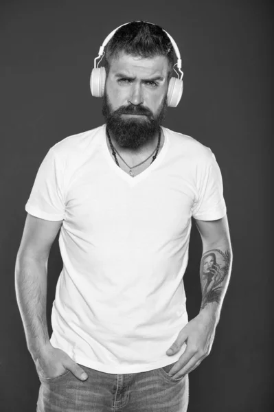 Najpierw muzyka. Nowoczesny hipster nosi stylowe słuchawki. Człowiek z brodą słucha współczesnej piosenki. Korzystanie z nowoczesnej technologii dla przyjemności. Gatunek muzyki współczesnej. Zabawa i rozrywka — Zdjęcie stockowe