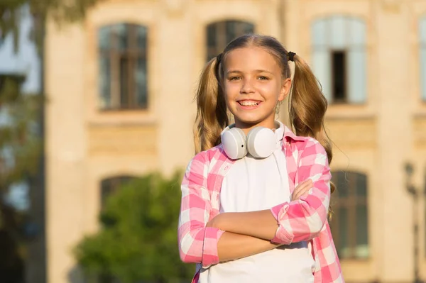 Kislány alkalmi stílus szabadban. Most kezdődik a tavaszi szünet. A kedvenc nyári lejátszási listája. gyermek zenét hallgatni. Mosolygó gyerek hallgatja a hangoskönyvet. Boldog iskolás lány hord fülhallgatót. középiskola — Stock Fotó