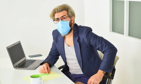 Avoid contact with other people. Stay home. Man wear medical mask work with laptop. Working from home. Online. Self isolation top response tactic for managing outbreak of COVID 19. Home office