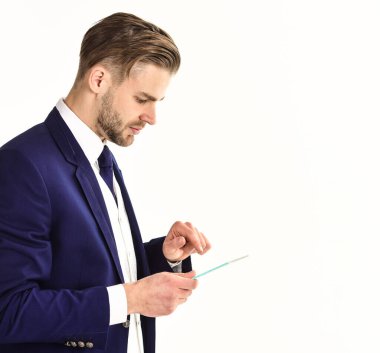 Koyu renk takım elbiseli iş adamı elinde tablet tutuyor.