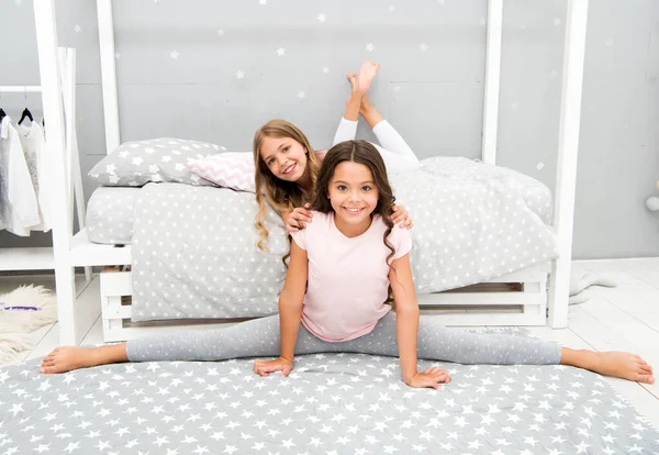 Bloqueo con utilidad. Ejercicio y estiramiento del cuerpo. Mejorar la flexibilidad. Estiramiento nocturno. Linda práctica de gimnasta dividida antes de acostarse. Las hermanas se preparan para ir a la cama. Niñas lindo pijama — Foto de Stock