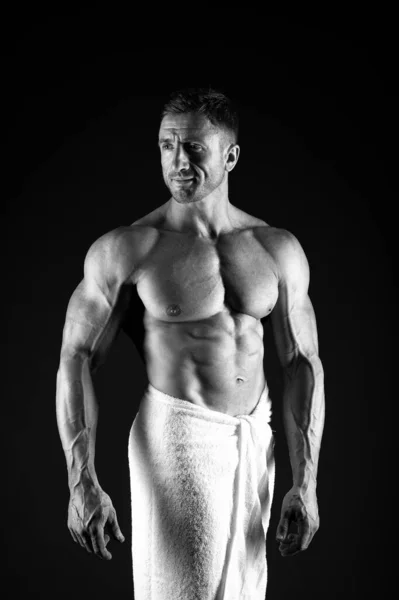 Prettige ochtend douche. Bodybuilder toont spieren. Sexy man in badhanddoek. Spierlichaam man na ochtend douche ontspannen. Bodybuilding concept. Sportman handdoektraining. Hygiëne van de lichaamsverzorging — Stockfoto