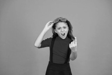 Gözlüklere odaklanıyorum. Havalı görünümlü turuncu arka plan öfkeyi hisset. Güzel ve şık bir çocuk. Katı, küçük kız okul üniforması. Eğlence için parti gözlükleri. çocuk moda konsepti