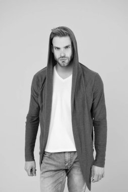 Yakışıklı ve sıradan biri. Yakışıklı adam sarı arka plan. Genç adam kapüşonlu sweatshirt giyiyor. Moda görünümlü yakışıklı bir manken. Moda ve tarz. Yakışıklı ve kendinden emin.