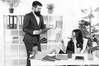 Patron ve çalışan. Kadın egemenliği. Erkek kadına karşı. İş yerindeki iş çifti. Erkek asistan çalışırken kendine güvenen iş kadını rahatlar. İş adamı tembel sekretere talimat verdi