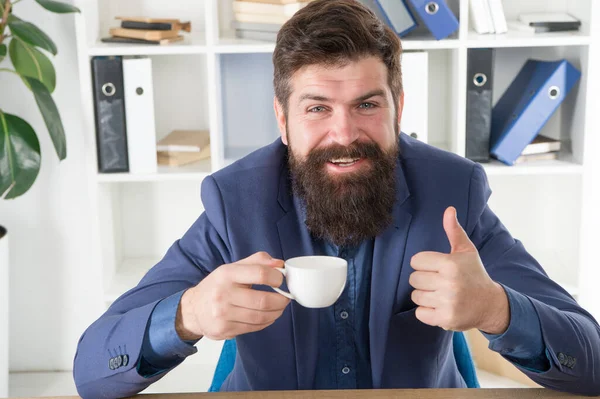 My energy. Man handsome boss sit in office drinking coffee. Comfy workspace. Good morning. Bearded hipster formal suit relaxing with coffee. Office life routines. Respectable ceo. First coffee