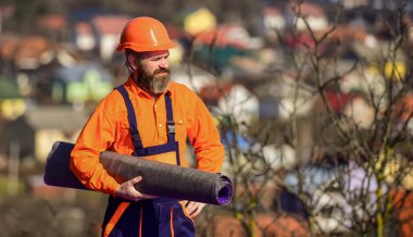 Bina binası. Çatı tamiri. Çatı kurulumu. Adam sert şapka dış mekan arka planında çalışıyor. Kiremit uygulamadan önce plastik kaplamaları, cam elyafları ya da eğimli çatılardan hissederek uygula