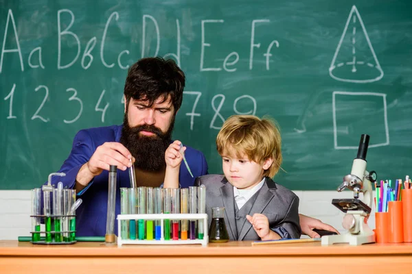 Inspirieren Sie den Nächsten. Laborforschung und -entwicklung. Chemie-Becher-Experiment. Reagenzgläser und Kolben mit farbigen Flüssigkeiten Vater und Sohn Kind in der Schule. bärtiger Mann Lehrer mit kleinem Jungen — Stockfoto