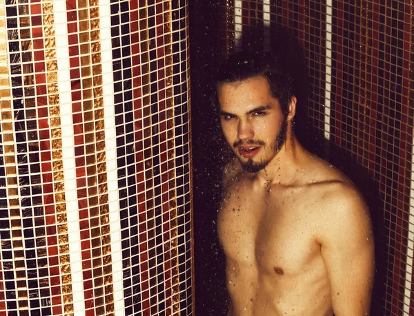 Yakışıklı kaslı seksi adam duşta yıkanıyor.
