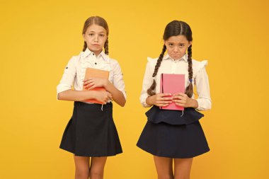 Mutsuz kitap kurtları. Sarı arka planda mutsuz küçük okul çocukları. Kitap tutan mutsuz duyguları olan sevimli küçük kızlar. Kötü işaretler yüzünden mutsuz