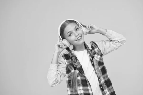 Щаслива дівчинка в сучасних навушниках. Мила дитина насолоджується стерео звуком. Бездротовий означає свободу. Навушники з бездротовими технологіями. Маленька дитина слухає музику сучасні бездротові навушники — стокове фото