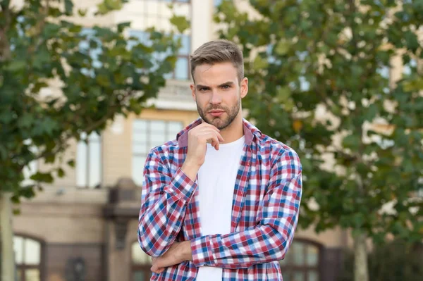 Jarní móda pro muže. Důvěrné postavení. Hezký chlapík stojí venku se zkříženýma rukama. Charismatický módní model. Pohledný neoholený muž. Muž nosí kostkovanou košili. Mužská krása a móda — Stock fotografie