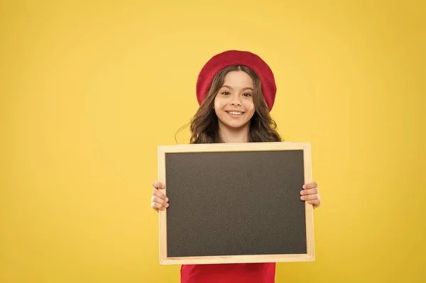 Placa de publicidade para a promoção. de volta à escola. vendas de compras da escola. criança no fundo amarelo. menina feliz em boina francesa. criança menina pequena com backboard da escola, espaço de cópia. publicação de negócios — Fotografia de Stock