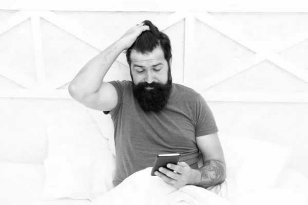 早上第一件事就是查电话 留胡子的男人在床上用手机。 用手机保持移动状态。 个人交流。 -早上好 醒来了。 保持联络的电话 — 图库照片