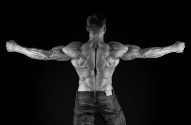 Profesyonel antrenör başarıları gösterir. Sırt egzersizleri. Vücut geliştirici mükemmel bir dikiz açısı. Güçlü vücut geliştirici kol kaslarını esnetiyor, siyah arka plan. Formda vücut geliştirici kaslı vücut gösteriyor.