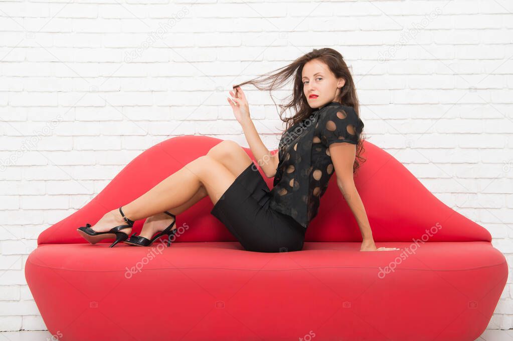 Never enough to be with her. beautiful girl sit on sofa. Sexy brunette businesswoman. desire and temptation. elegant beauty on couch. fashion model has sexy smooth legs. sexy woman resting on sofa