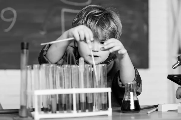 Ένα μικρό παιδί μαθαίνει χημεία στο σχολικό εργαστήριο. Πειραματίζεται με χημικά. Μικρό αγόρι σε χημικό ντουλάπι. Ένα παιδί με εργαστηριακή ποδιά να μαθαίνει χημεία. Πίσω στο σχολείο. Δοκιμή δείγματος αίματος — Φωτογραφία Αρχείου