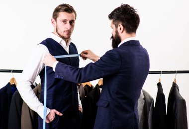 İşadamı ve müşteri terzi çalışırken takım elbiselilerle askıda bekliyor..