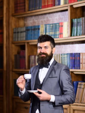 Eski bir kafede kahve içen kıdemli bir işadamı.
