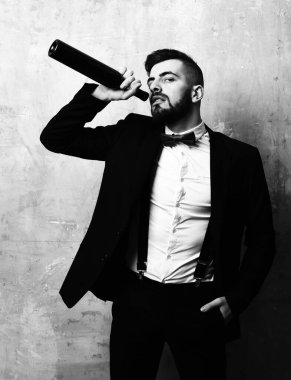 Takım elbiseli ve kırmızı papyonlu adam şarap içer.