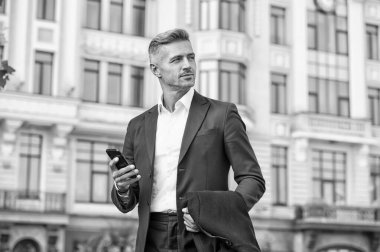 Modern iletişim. İş adamı cep telefonunu tutar. Dışarıda cep telefonu olan yakışıklı bir adam. Profesyonel kullanım için telefon. Taşınabilir yaşam tarzı. İş iletişimi. Yeni teknoloji. Çevrimiçi iletişim