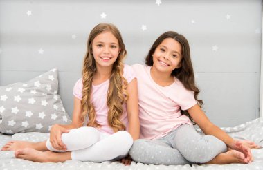 İyi sabahlar. Pijamalı çocuklar. Evde kal. Bütün gün pijama. Küçük kızlar için şirin, rahat bir yatak odası. Kız kardeşler yatak odasının içinde eğleniyor. Çocukluk konsepti. Yatak odası rahatla ve dinlenmene bak.