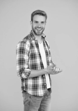 Kareli gömlek ve kot pantolon giymiş yakışıklı bir adam. Mutlu öğrenci sarı arka planı. İyi görünmesini sağla. Erkekler için sıradan moda. Erkeksi kıyafetler ve bak. Şık giyinmiş şık bir erkek. pozitif duygular