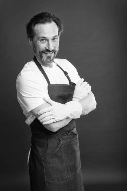 O beceriklidir. Kırmızı arka planda mutlu bir kahya. Olgun hizmetçi eldiven ve önlük giyer. Profesyonel temizlikçi. Hizmetçi ya da hizmetçi. Oda temizliği uzmanı. Yurt içi asistan