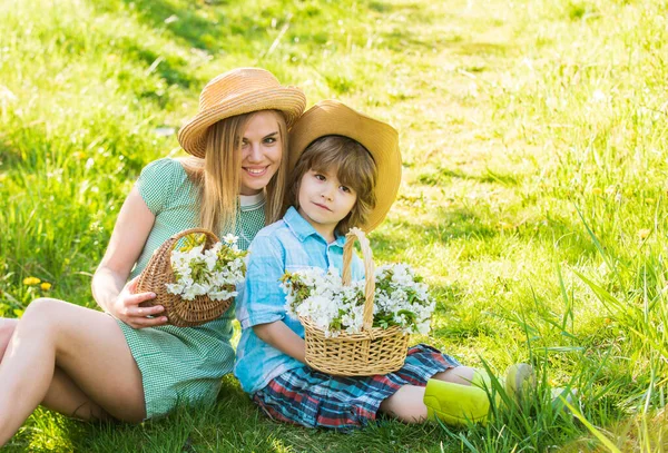 Vacances de printemps. Fleurs sauvages dans les champs. Joyeuses fêtes. Mère et mignon fils portent des chapeaux. Ferme familiale. Le bonheur maternel. Famille Cowboy ramassant des fleurs dans des paniers. Beau fond de nature familiale — Photo