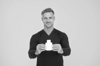 Heyecan verici erkek parfümü. Mutlu adam parfüm şişesini sarı arka planda tutuyor. Parfüm sunan yakışıklı bir adam. Eau de Tuvalet. Kozmetik ürünü. Kozmetik. Parfüm reklamı. Parfüm markası, boşluğu kopyala