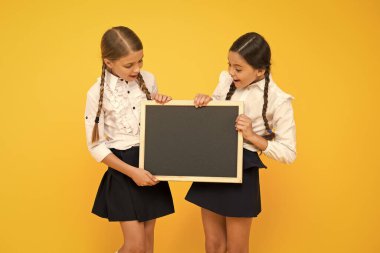 Önce eğitim. Sarı arka planda eğitim için boş tahta tutan küçük çocuklar. Zorunlu ilkokulda eğitim. Resmi bir eğitim alma, kopya alanı