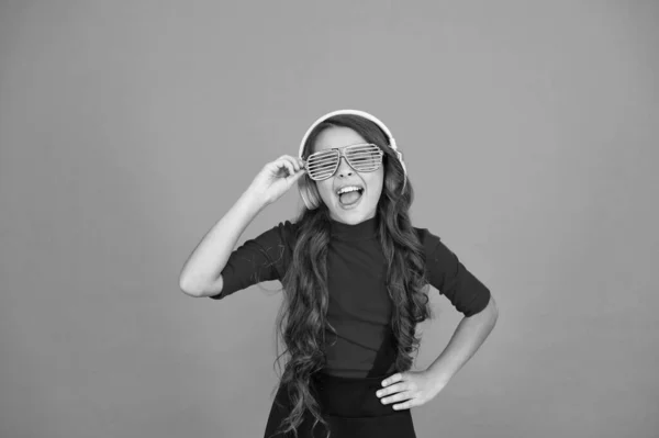 Utilizzando cuffie wireless per DJ disco. piccola ragazza felice ascoltare musica in cuffia. bambino divertente in bicchieri da festa. tempo divertendosi. Ai bambini moderni piace la musica. sentimento elegante e fiducioso. scuola radio dj — Foto Stock