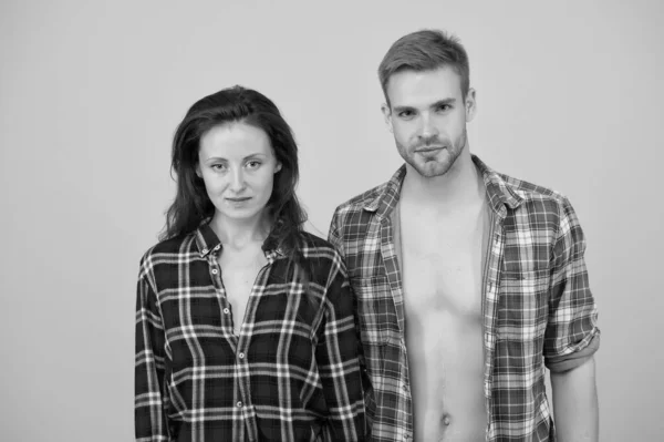 confident couple portrait. Rustic hipster style. handsome man with bare chest. attractive woman long hair. casual couple on yellow background. happy valentines day. man and woman checkered shirt