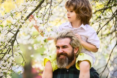 Babalar Günü. Baba ve oğul. Gelmiş geçmiş en iyi baba. Çocuk babasıyla eğleniyor. Mutlu bir aile. Doğada yaşayan küçük bir çocuk ve baba. İlkbahar. Hippi bebeği sırtında taşıyor. Sakallı zalim adam İyi baba