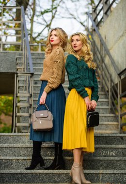 Süveter etek modası. Birbirimizi tamamlıyoruz. Eşleşen kıyafetler. Kadın kardeşler dışarıda arka planda. Vogue konsepti. Sarışın kızlar aynı kıyafetleri giyer. Renkler uyuşuyor. Kişisel stilist servisi