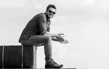 Macera zahmete değer. Gezgin, uçuşu bekle. Çekil şuradan. Seksi erkek gökyüzü arka planı. Maço, tıraşsız bir adam tur çantasına oturur. Erkek modası. Çok modaya uygun görünüyorsun. Gözlüklü iş adamı. iş gezisi