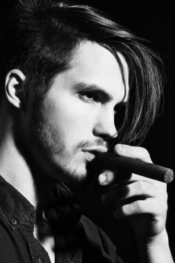 Ciddi sakallı adam puro içiyor.