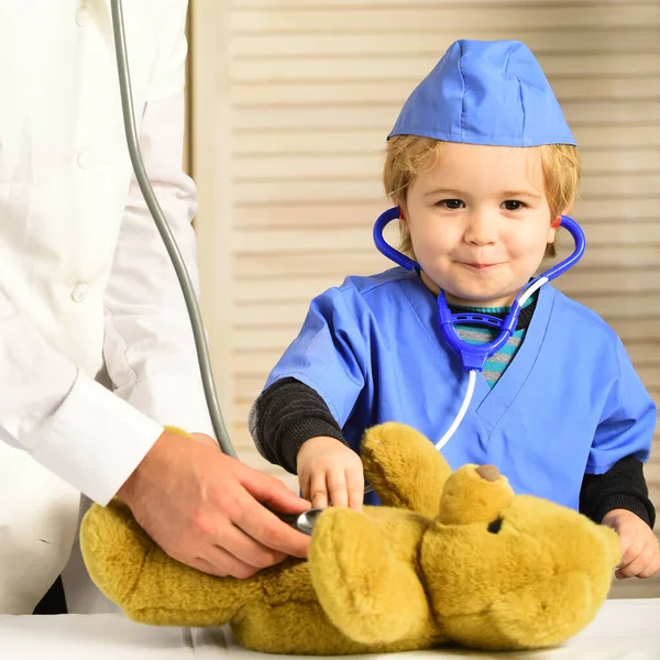 Concepto de salud e infancia. Pequeño asistente examina osito de peluche . —  Fotos de Stock