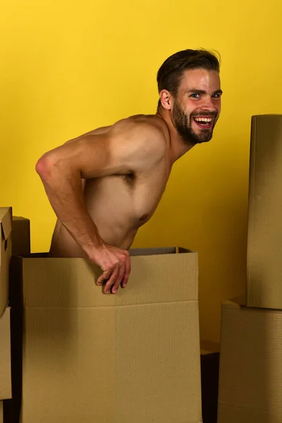 Uomo seduto nudo tra scatole di cartone e ridendo — Foto Stock