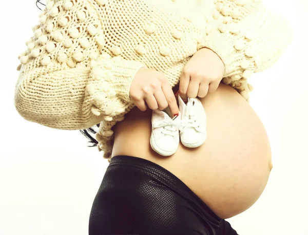 Ženské ruce těhotné ženy drží dětské boty na břiše — Stock fotografie