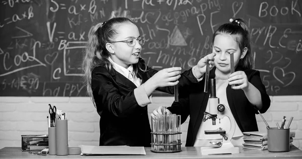 Oktatási kísérlet koncepció. A lányok kémiát tanulnak. Mikroszkóp és kémcsövek az asztalon. Vegyi reakciókat végrehajtani. Alapismeretek a kémiáról. Tedd érdekessé a kémiát. — Stock Fotó