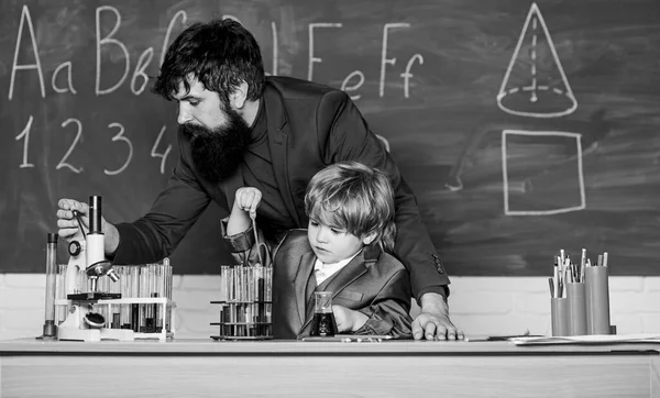 Δάσκαλος άνθρωπος με μικρό αγόρι. Εξοπλισμός εργαστηρίου σχολείου. φοιτητής που κάνει επιστημονικά πειράματα με μικροσκόπιο στο εργαστήριο. Πίσω στο σχολείο. Πατέρας και γιος στο σχολείο. χρησιμοποιώντας μικροσκόπιο στο εργαστήριο. Ζώντας στην ψηφιακή εποχή — Φωτογραφία Αρχείου