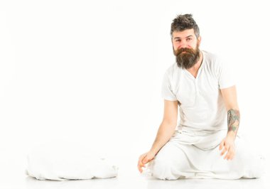 Sakallı hippi yastığın yanında oturuyor, uykulu, gülümseyen maço..