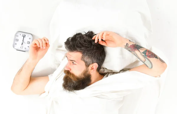 El hombre con barba yace en sábanas y almohadas, espera —  Fotos de Stock