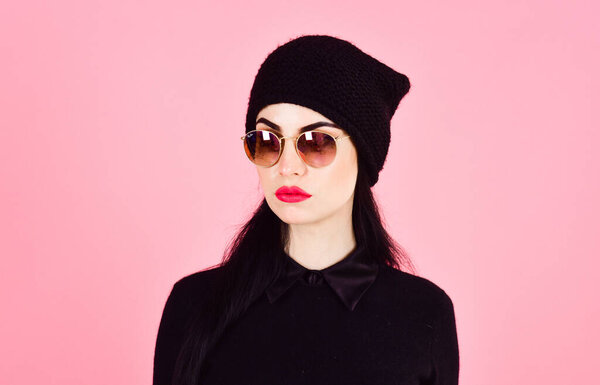 Woman in stylish clothes wears hat and sunglasses.