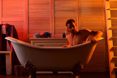 Banyoda romantik ışıkları ve merdivenleri olan bir adam var.