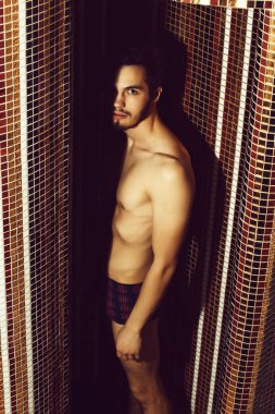 Renkli mozaik arka planda duşta yakışıklı bir adam.