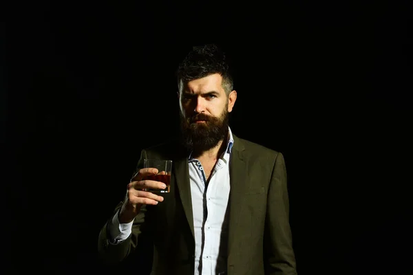 Человек с серьезным лицом в костюме держит стакан алкоголя — стоковое фото