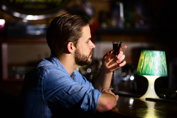 Homem com barba bebe álcool no bar em fundo embaçado . — Fotografia de Stock