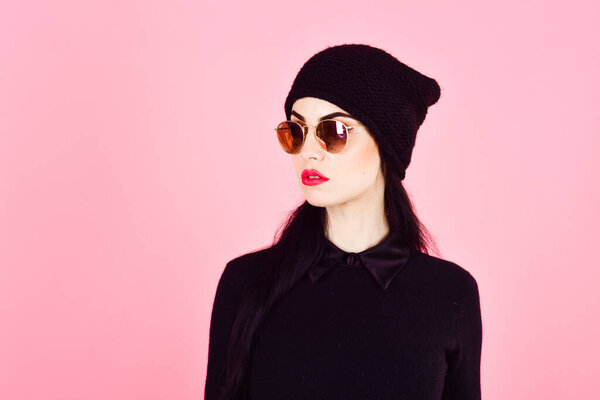 Woman in stylish clothes wears hat and sunglasses.